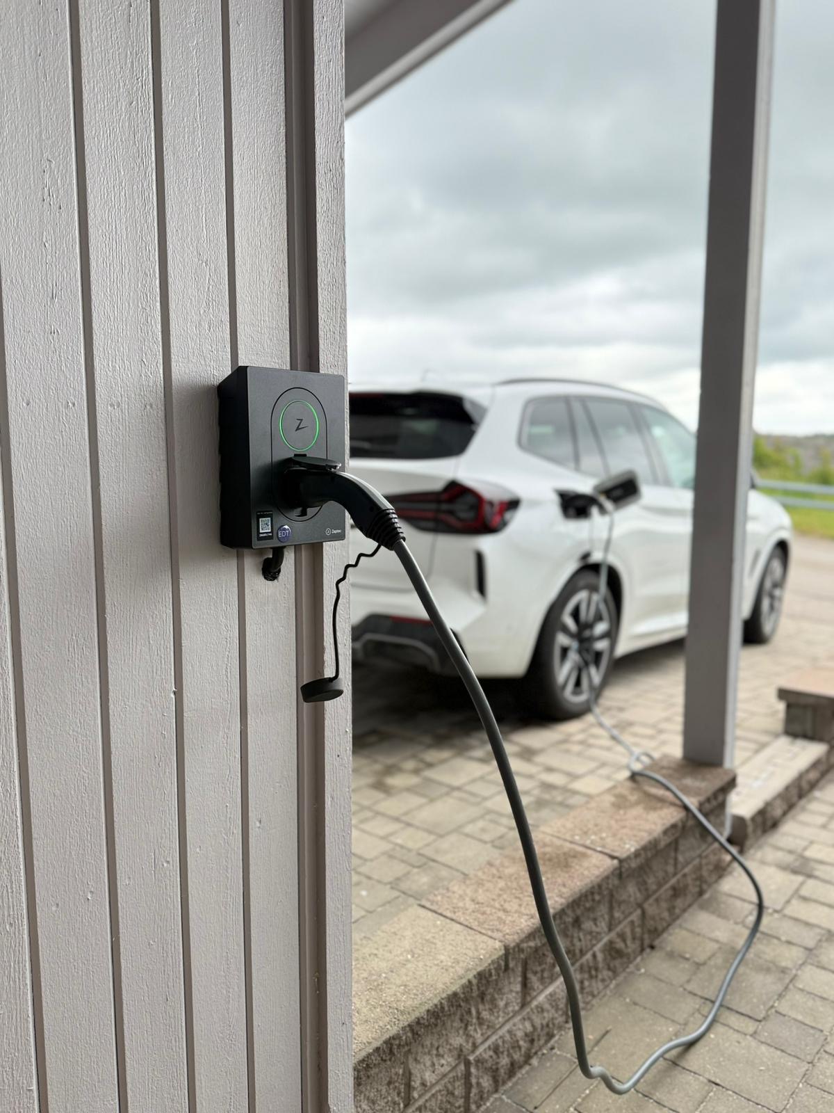 Elbil laddas med väggmonterad laddbox hemma på garageuppfarten